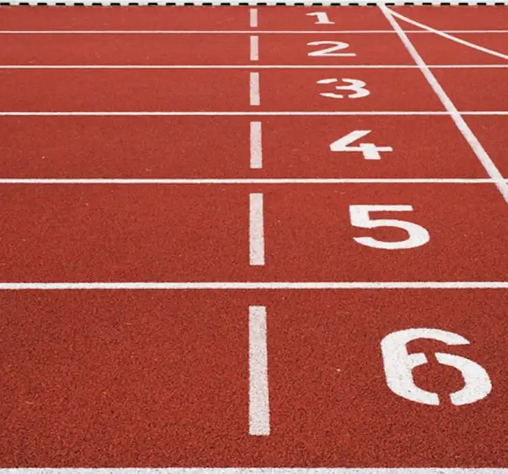 Uma pista de atletismo vermelha com seis corredores numerados de 1 a 6 em branco. A vista está orientada para a linha de chegada, sugerindo um sentimento de preparação e antecipação.